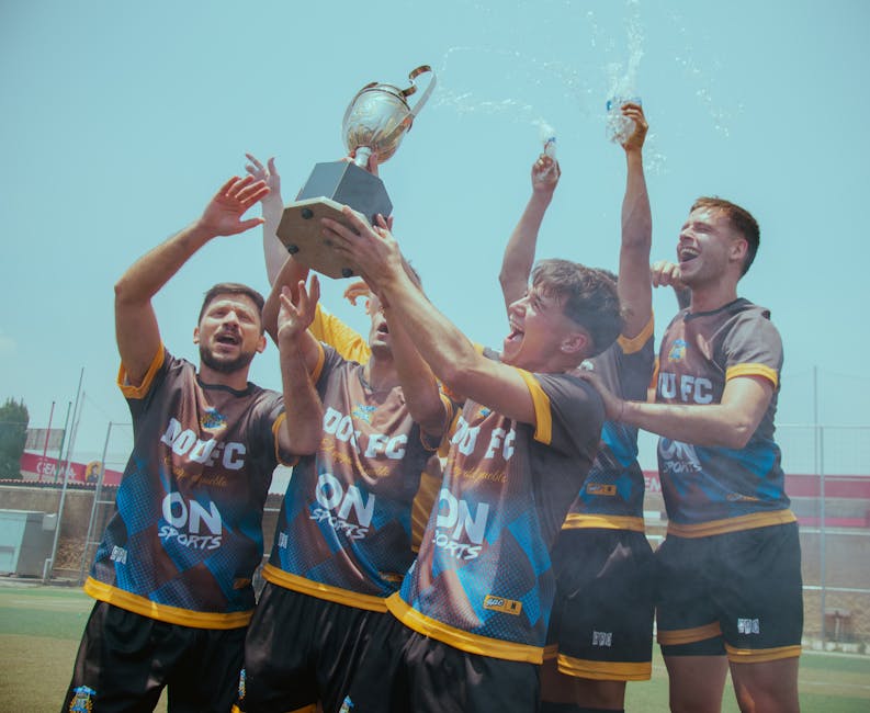A jubilant soccer team celebrates their championship victory by raising a trophy outdoors.